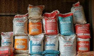 Bags of various animal feed for poultry, cattle, and pets stacked on a farm floor